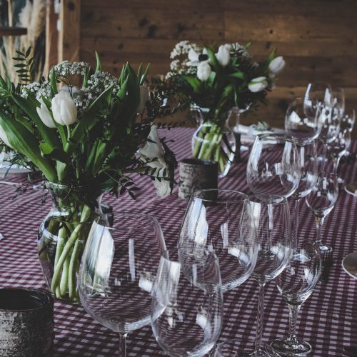 Gedeckter Tisch mit Weingläsern und weißen Blumensträußen